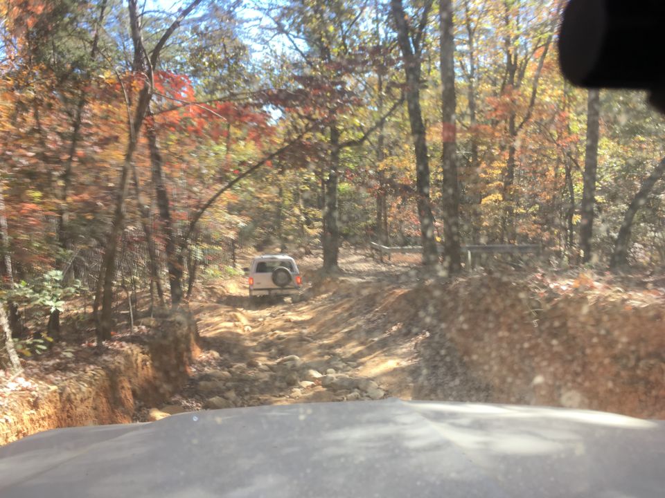 White SUV on a rocky forest trail in autumn.