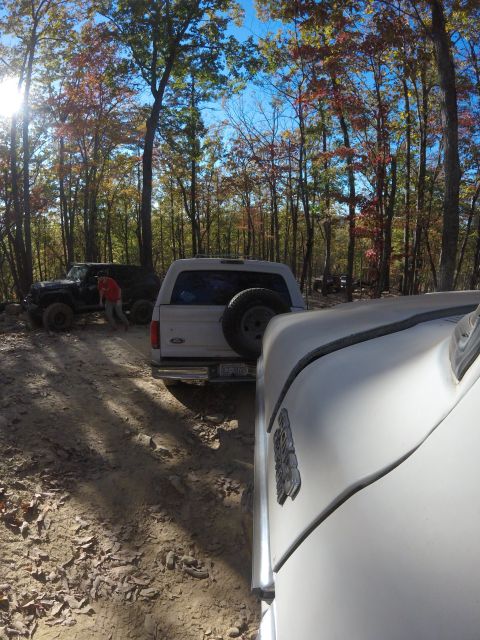 1979 Ford Bronco - A white Ford Bronco is parked on a dirt trail surrounded by trees with fall foliage. Another dark colored Jeep is parked behind it, and a p…