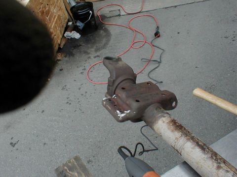 1983 Ford Bronco - A rusty Dana-style solid front axle housing center section lying on a concrete garage floor, its differential pinion snout and cast tube st…