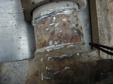 1983 Ford Bronco - Tight close-up of a rusty steel sleeve welded onto an axle tube, with fresh stack-of-dimes weld beads running around both ends of the sleev…