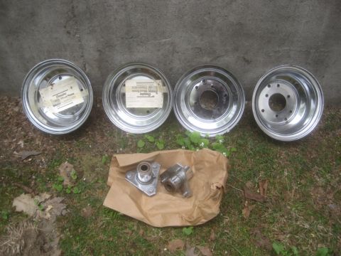 1986 Yamaha BLASTER - Four chrome wheels and two metal parts are laid out on the grass in front of a concrete wall.