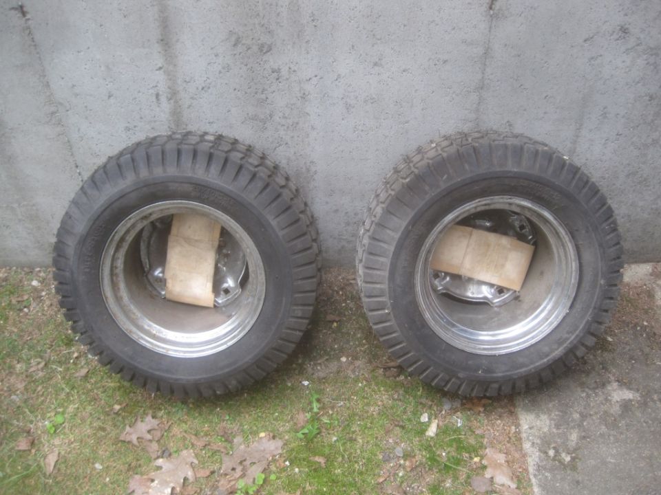 Two tires and rims with chrome centers, resting on grass