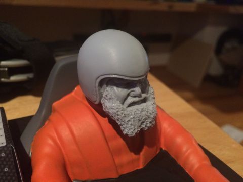1989 Ford Bronco - This is a model of a man wearing a helmet and an orange suit, likely a driver figure for a model car.