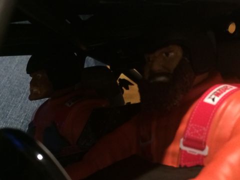 1989 Ford Bronco - Two figures in racing suits are visible inside a vehicle's interior.