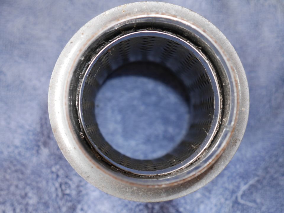 Inside of a perforated metal exhaust pipe component.