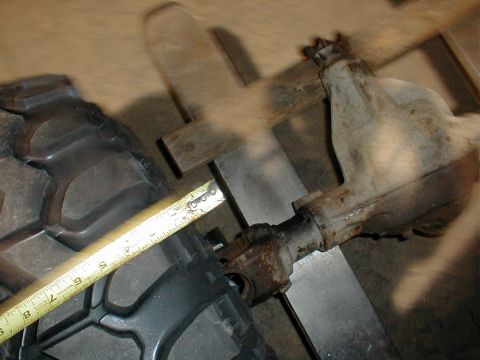 1983 Ford Bronco - A tape measure stretched across a rusty cast axle housing and its steel tube, checking a dimension during a driveline mock-up on a shop flo…