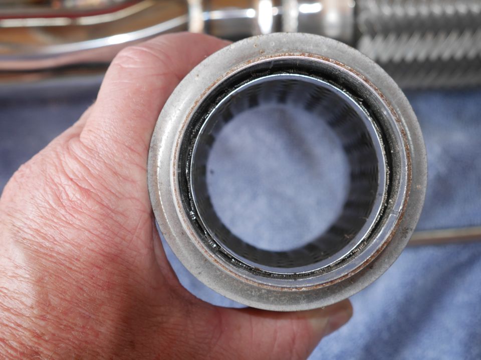 Close-up of a vehicle exhaust component held in a hand.