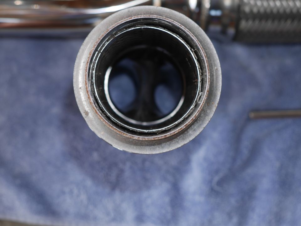 Close-up of an exhaust pipe opening with a blue cloth below.