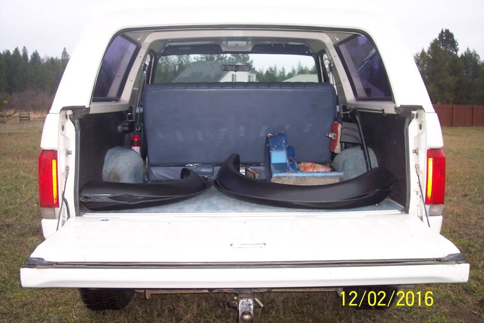 1990 Ford Bronco rear interior showing blue seats, fire extinguisher, and two black fender flares