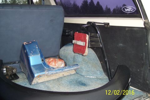 1990 Ford Bronco - The interior of a vehicle shows a blue plastic part and a red sponge, with a Ford logo visible on the rear window.