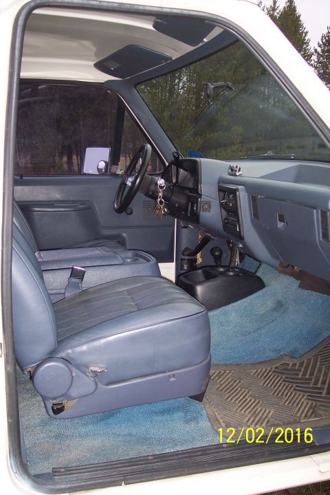 1990 Ford Bronco - The interior of a 1990 Ford Bronco is visible, blue upholstery and a dashboard with a steering wheel and keys.
