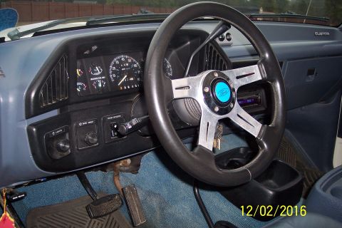 1990 Ford Bronco - The interior of a Ford Bronco shows the dashboard with a custom steering wheel, instrument cluster, and various controls. The driver's side…