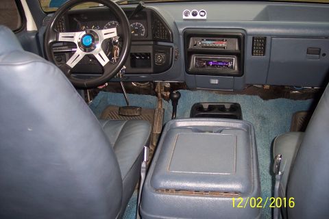 1990 Ford Bronco - The interior of a Ford Bronco is shown, featuring blue leather seats, a custom steering wheel, and aftermarket car stereo. The dashboard ha…
