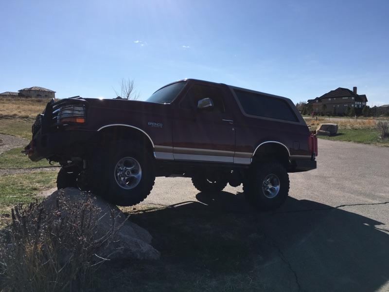 Maroon 1996 Ford Bronco on a rock, front tires elevated.