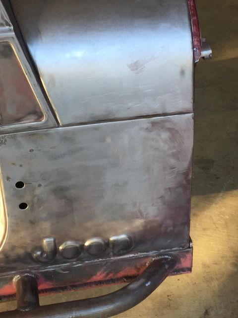 1985 Jeep CJ7 - A close-up of the bare metal body of a Jeep CJ7 shows the embossed "JEEP" lettering along the lower section. The vehicle appears to be unde…