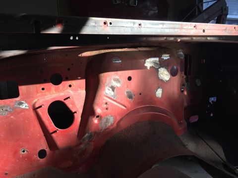 1985 Jeep CJ7 - This is a close-up interior shot of the firewall area of a red vehicle undergoing restoration. Several patches of body filler are visible o…