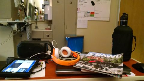 1985 Jeep CJ7 - A desk with a tablet, headphones, a magazine, and a water bottle in what appears to be a medical setting.