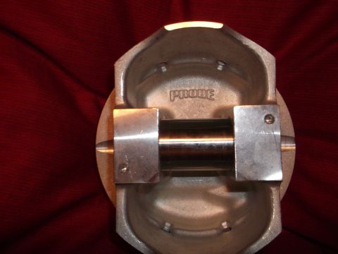 1971 Ford Ranchero - A close-up, overhead view of a piston with the word "PROBE" stamped on it. The piston is resting on a red, textured surface.