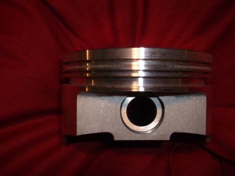 1971 Ford Ranchero - A close-up of a piston, likely from a Ford Ranchero, is shown against a red fabric background. The piston features multiple grooves for rin…