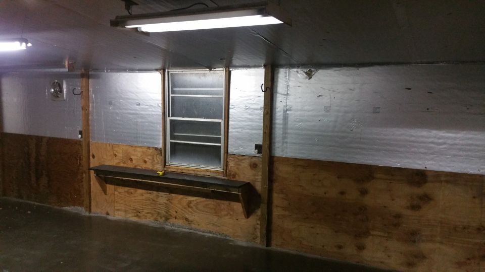 Interior of a structure with insulated walls, a window, and a shelf.