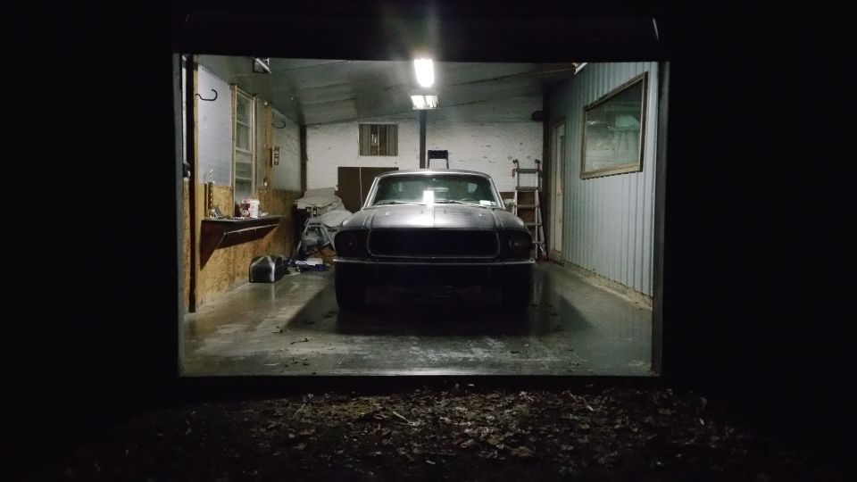 Front view of a dark classic car in a garage at night.