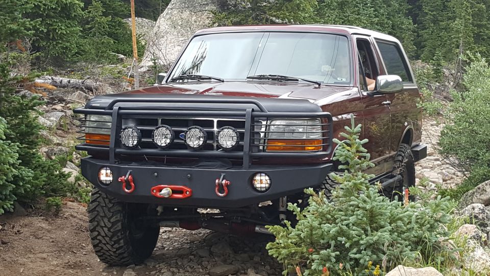 1996 Ford Bronco on a rocky trail with a brush guard and custom bumper.