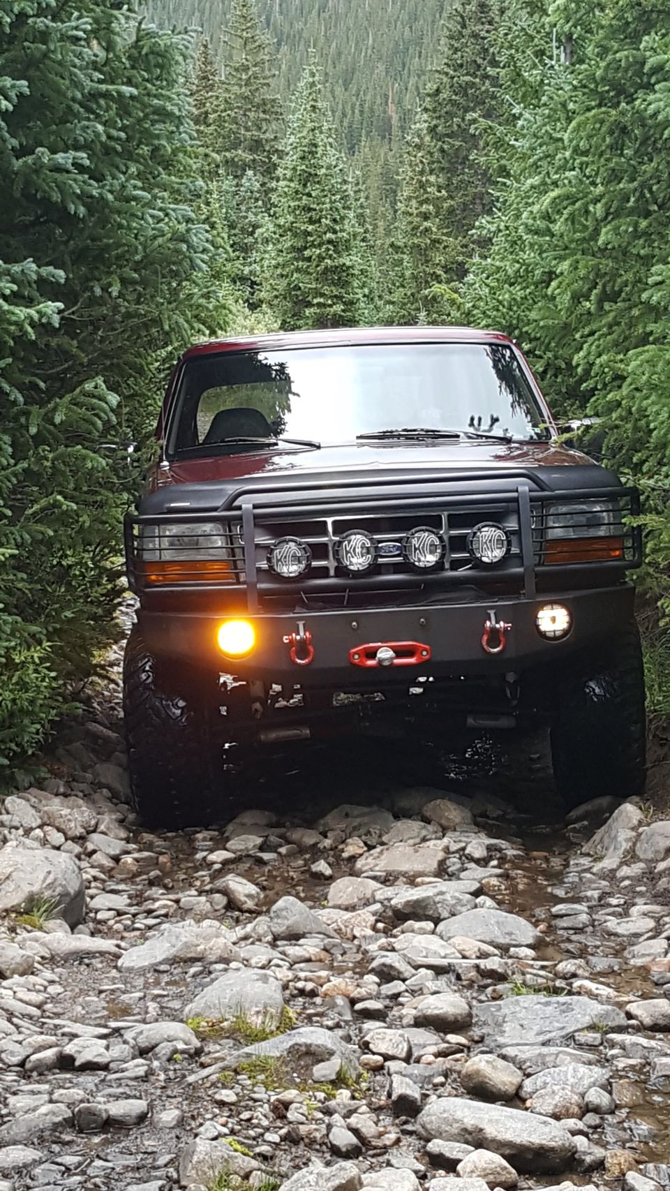 1996 Ford Bronco on a rocky trail, front view with KC lights and winch.
