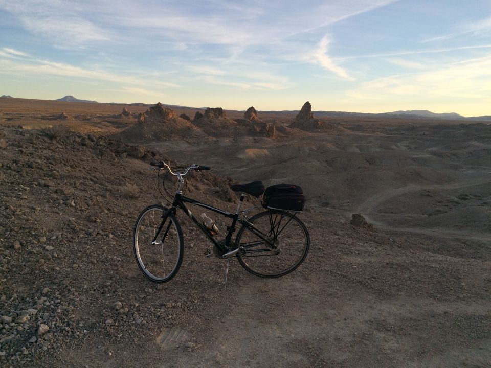 Black bicycle parked on a rocky hill with tufa formations in the distance.