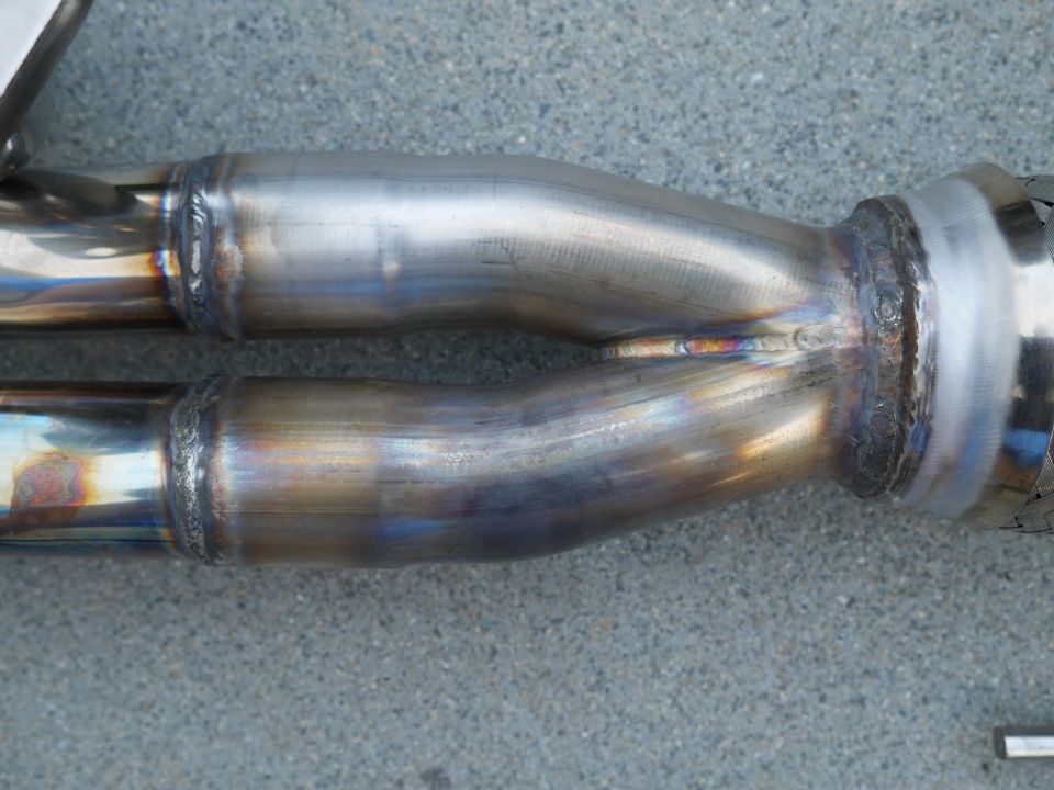 Close-up of a Y-shaped exhaust pipe with visible welds and heat discoloration