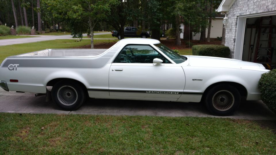 White Ford Ranchero GT in side profile parked on driveway by brick house