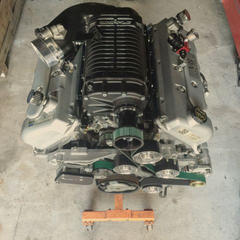 2004 Ford Crown Victoria - A supercharged V8 engine is displayed on an engine stand, showing its complex belt system and intake.