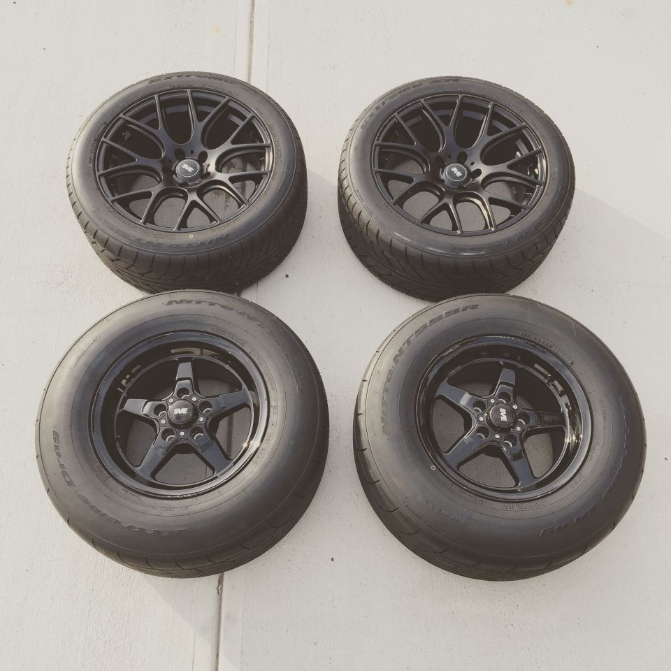 Four black wheels and tires, two with five-spoke design, two with mesh design