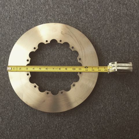 2004 Ford Crown Victoria - Measuring a brake rotor with a tape measure. The rotor has multiple bolt holes around its circumference.