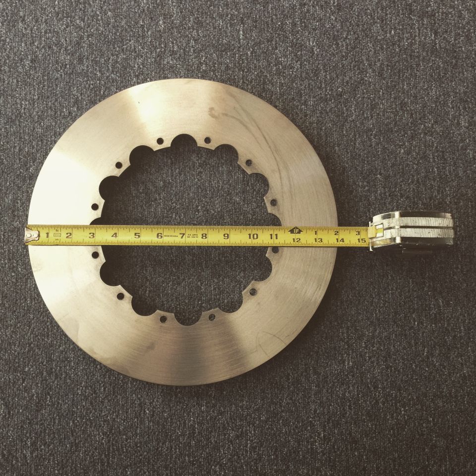 Brake rotor with a yellow measuring tape across it. The tape shows measurements up to 15 inches