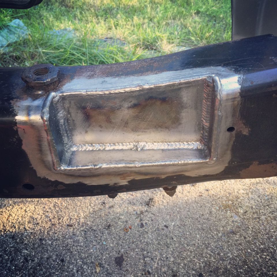 Close-up of a metal patch welded onto a vehicle frame, likely a repair