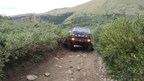 1996 Ford Bronco - This 1996 Ford Bronco is tackling a challenging off-road path in a mountainous landscape.