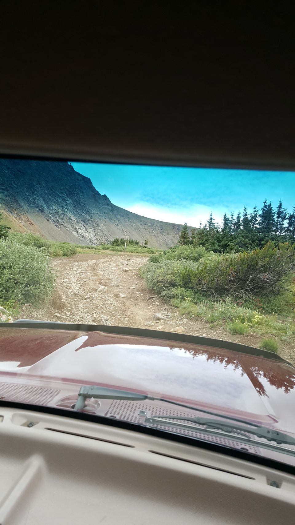 Red vehicle interior looking out at mountain road; Supermotors.net logo visible