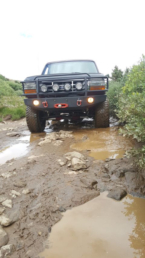 1996 Ford Bronco - 1996 Ford Bronco navigating a challenging muddy off-road path.