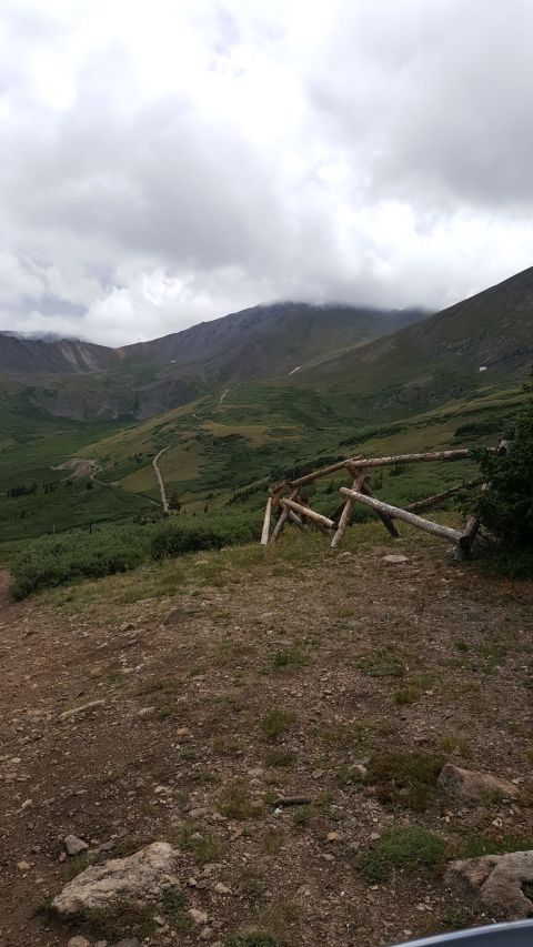 1996 Ford Bronco - A scenic view of a mountain range under a cloudy sky, with a wooden fence marking the edge of a trail.