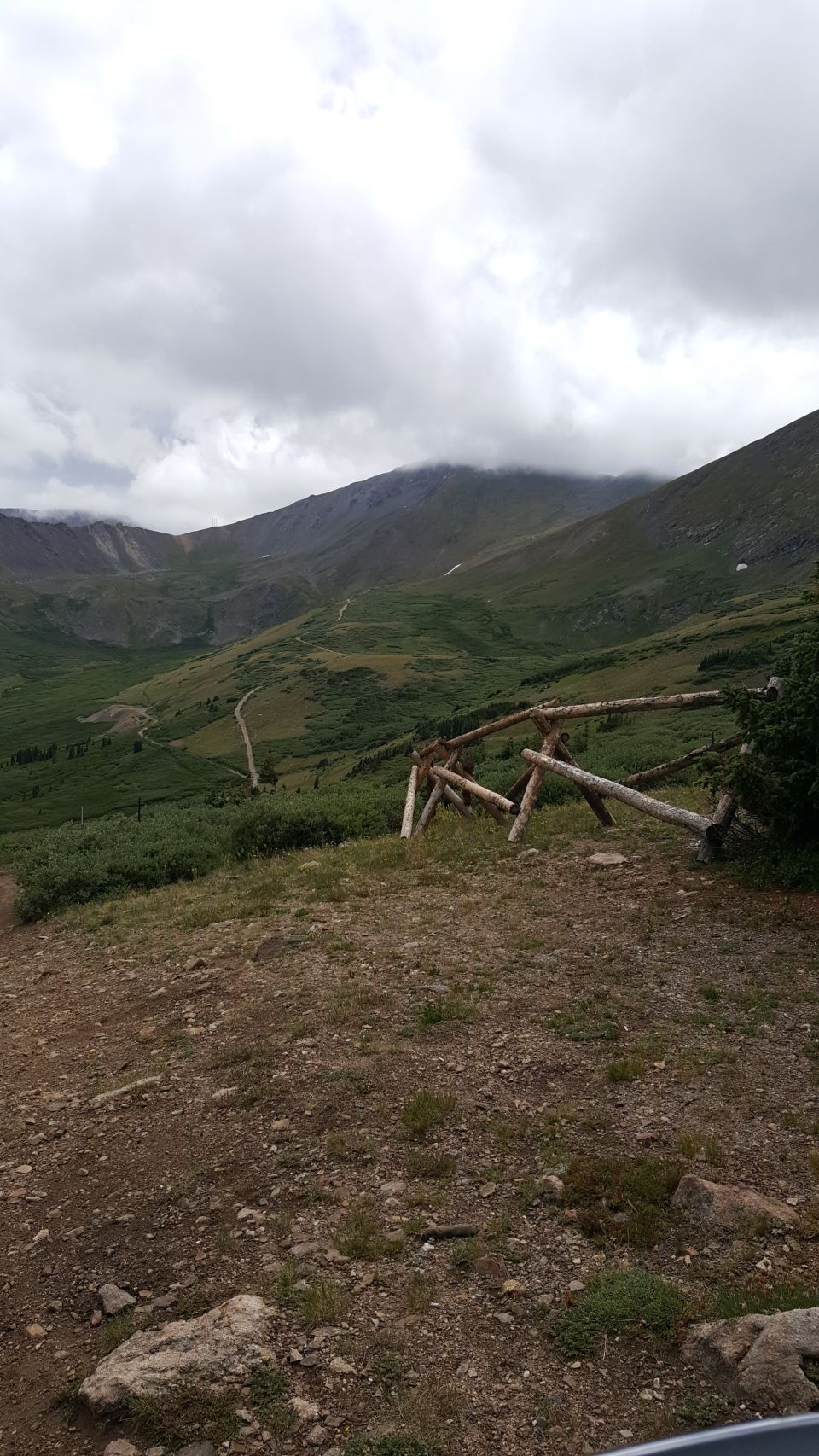 Mountain valley with a cloudy sky and a rustic wooden fence in the foreground