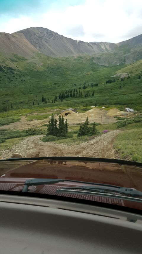 1996 Ford Bronco - View from inside a vehicle driving on a dirt road through a mountainous landscape.
