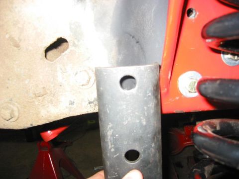 1985 Ford Bronco - A metal bracket is held near a vehicle's frame, suggesting a modification or repair.