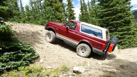1996 Ford Bronco - This red 1996 Ford Bronco navigates a steep, rocky incline on a mountain trail.