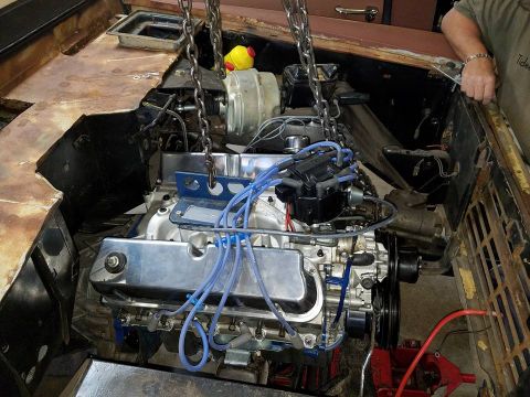 1972 Ford Bronco - Engine installation in progress, showing the engine being carefully lowered into the vehicle's engine bay.