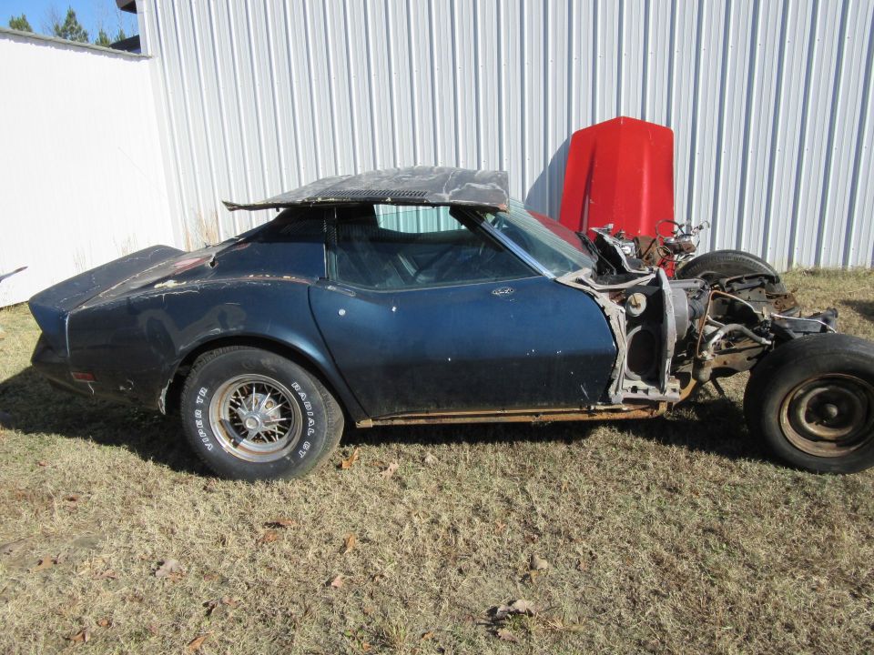 Dark blue Chevrolet Corvette missing front end and hood, parked on grass