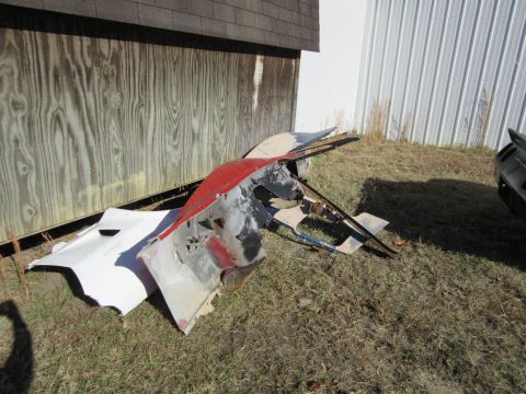 Wrecked red and white car parts on grass