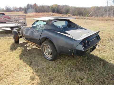1976 Chevrolet Corvette, missing parts, on a trailer in a grassy field