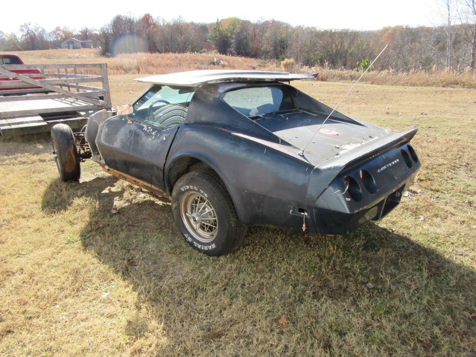 1976 Chevrolet Corvette, missing parts, on a trailer in a grassy field