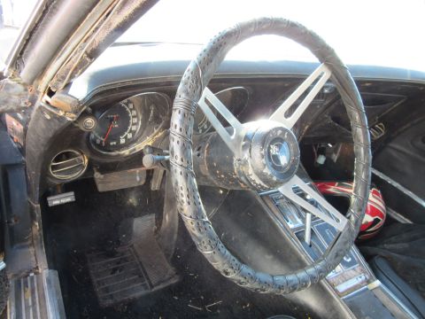1976 Chevrolet Corvette interior with cracked steering wheel and dashboard gauges