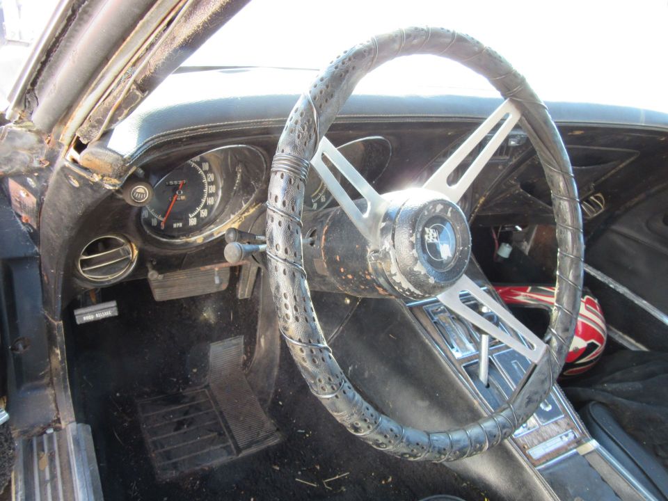 1976 Chevrolet Corvette interior with cracked steering wheel and dashboard gauges